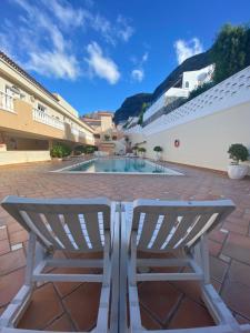 un paio di sedie sedute accanto alla piscina di Buenavista Top Floor Penthouse a Santiago del Teide