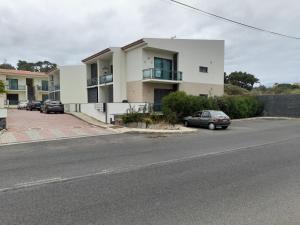 a white building with cars parked in a parking lot at Vilas Horizonte in Porto Santo