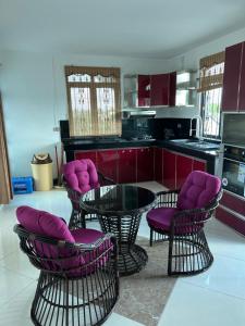 a kitchen with purple chairs and a glass table at Indira Villa 3 in Roche Terre