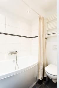 a white bathroom with a tub and a toilet at Apartmá Zeyer 1887 in Karlovy Vary
