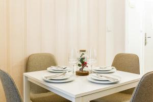 a white table with chairs and plates and wine glasses at Apartmá Zeyer 1887 in Karlovy Vary