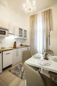 a kitchen with a white table and chairs and a kitchen with a dining room at Apartmá Zeyer 1887 in Karlovy Vary