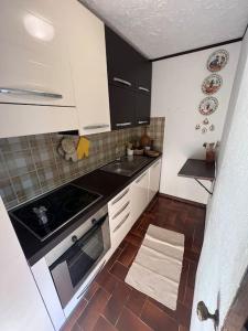 a small kitchen with white cabinets and a stove at Appartamento vista Alpi nel centro storico in Sauze dʼOulx