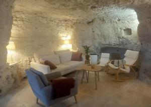 a living room with a white couch and chairs at Troglo entre Caves et Châteaux in Montlouis-sur-Loire