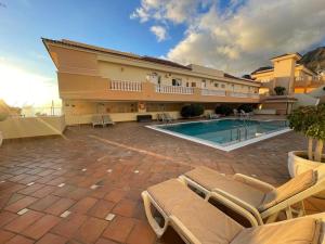 a large building with a swimming pool and some chairs at Buenavista Top Floor Penthouse in Santiago del Teide