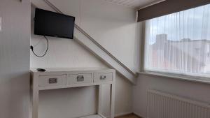 a living room with a tv on the wall next to a window at Appartement met 3 slaapkamers vlakbij strand en centrum in Zoutelande