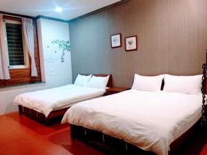 een slaapkamer met 2 bedden en witte lakens bij Ju Jia Xiao Zhan Homestay in Guanshan