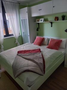 1 dormitorio con 1 cama grande con almohadas rojas en Apartman LeDa - Ski centar Ravna Planina Gornje Pale, en Pale