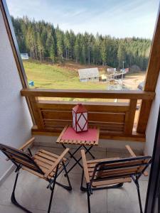 einen Tisch und zwei Stühle auf einem Balkon mit Fenster in der Unterkunft Apartman LeDa - Ski centar Ravna Planina Gornje Pale in Pale