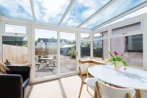 a conservatory with a table and chairs and windows at No27 Willowbank in Dunkeld