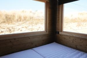 a bed in a room with two windows at Dünencamping Amrum in Wittdün