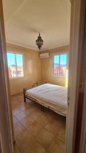 een slaapkamer met een groot bed en 2 ramen bij Appartement te huur in Marrakech in Marrakesh