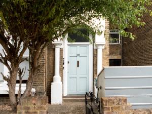 a blue door on a brick house with a tree at Pass the Keys Stylish cosy 2bed near Finsbury Park w balcony in London