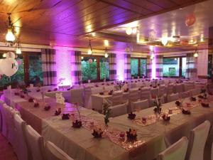 un salón de banquetes con mesas y sillas blancas e iluminación púrpura en Siegerland-Hotel, en Freudenberg