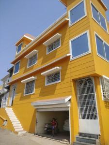 a yellow building with two people in front of it at 1BHK AC Service Apartment 202 in Pune