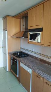 a kitchen with wooden cabinets and a stove top oven at APARTAMENTO LUMINOSO EN URBANIZACIÓN PRIVADA in Granada