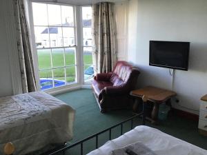 a room with a couch and a chair and a television at Sea View Guest House in Hartlepool