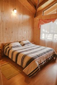 a bed in a wooden room with a window at Cabañas Alto Puelo Patagonia Verde in Puelo