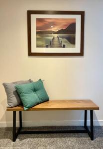 una panca di legno seduta contro un muro con un'immagine di Vennel Street Apartments a Stewarton