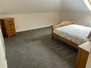 a bedroom with a bed and a dresser in it at Vennel Street Apartments in Stewarton