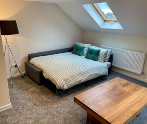 a bedroom with a bed and a table and a skylight at Vennel Street Apartments in Stewarton +12 photos