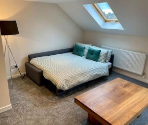 a bedroom with a bed and a table and a skylight at Vennel Street Apartments in Stewarton