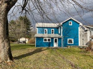 een blauw huis in een tuin met een boom bij Cozy, historic 5-bedroom home in Amish country in Smicksburg