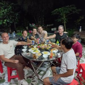 Garden House Côn Đảo في كون داو: مجموعة من الناس يجلسون حول طاولة يأكلون الطعام