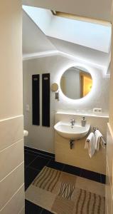 ein Bad mit einem Waschbecken und einem Spiegel in der Unterkunft Wiefarn Apartments - Ferienwohnungen in Bad Wiessee am Tegernsee in Bad Wiessee