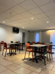 a dining room with tables and chairs and a tv at Hotel Inn Design Le Havre in Montivilliers