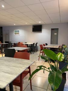 a dining room with tables and chairs and a plant at Hotel Inn Design Le Havre in Montivilliers