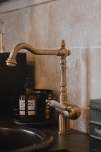 La salle de bains est pourvue d'un lavabo avec un robinet en or sur un comptoir. dans l'établissement LA SALLE DES SORTILÈGES, à Perpignan