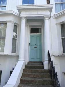 a blue door on a white house with stairs at Newly refurbished 2-bedroom flat in Notting Hill in London