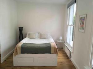 Cama blanca en habitación blanca con ventana en Newly refurbished 2-bedroom flat in Notting Hill en Londres