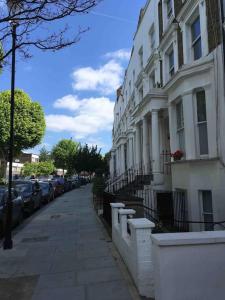 uma rua com carros estacionados ao lado de um edifício branco em Newly refurbished 2-bedroom flat in Notting Hill em Londres
