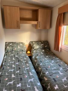 two beds in a small room with cabinets at Turnberry Holiday Home in Turnberry