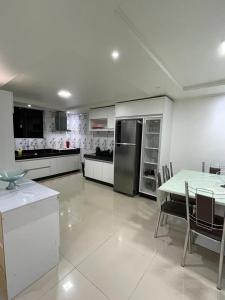 a large white kitchen with a table and refrigerator at Cantinho Almeida in Alto Paraíso de Goiás