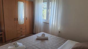 a bedroom with two towels on a bed with a window at Apartments Irena in Božava