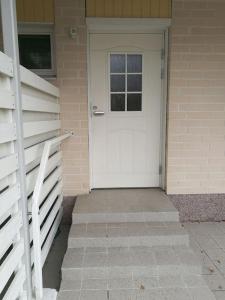 una puerta blanca en una casa de ladrillo con porche en Cosy studio apartment near by Ideapark, en Lempäälä