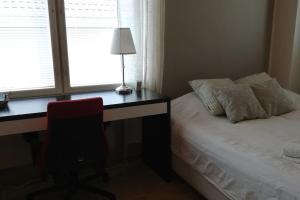 1 dormitorio con escritorio, cama y lámpara en Cosy studio apartment near by Ideapark, en Lempäälä