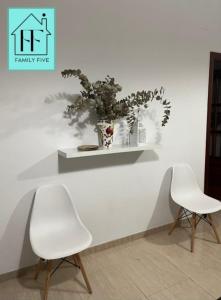 two white chairs and a shelf with a plant on it at FAMILY FIVE in Córdoba