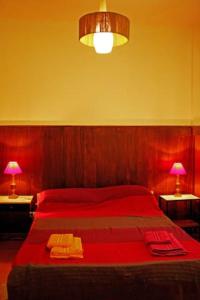 1 dormitorio con 1 cama roja, 2 mesas y 2 lámparas en Pinamar departamento, edificio Atlántico en Pinamar