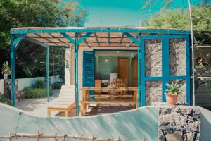 uma pérgola azul com uma mesa de madeira e um banco em Casa Madeira em Porto Novo