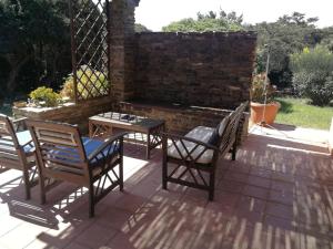 un patio con sedie, un tavolo e un muro di mattoni di L' Elicriso, a pochi passi dal mare con giardino privato - The Elicriso, a few meters from the sea, with private garden a Stintino