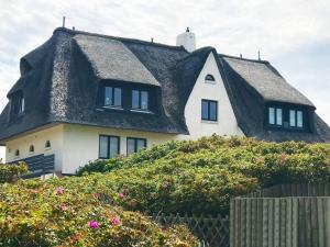 una casa con techo de paja en la cima de una colina en Ocean-View-I-Holiday-Apartments-Sylt, en Rantum