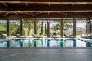 a swimming pool in a house with chairs and windows at Il Boscareto Resort & Spa in Serralunga d'Alba