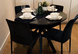 Colindale的住宿－Lavish 2 Bedroom Apartment，黑色餐桌,配有黑色椅子和盘子,酒杯
