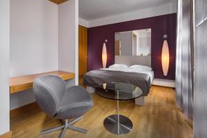 a bedroom with a bed and a chair and a mirror at Mamaison Residence Belgická Prague in Prague