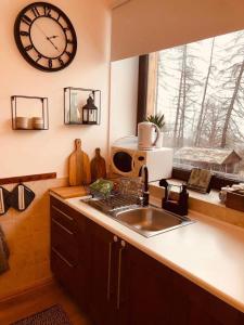 a kitchen with a sink and a clock on the wall at Larix Mátra Vendégház in Matraszentlaszlo +18 photos
