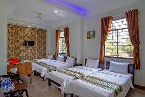 a hotel room with three beds and a tv at NGOC LINH MOTEL in áº¤p VÄ©nh ÃÃ´ng